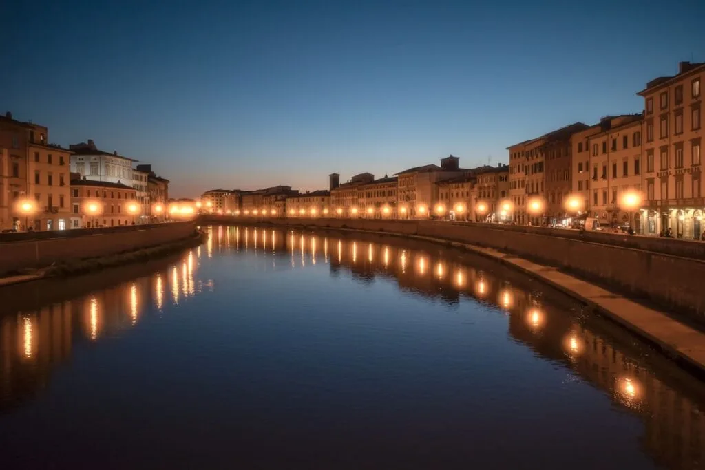 Widok na rzekę Arno w Pizie z odbiciami lamp o zmierzchu