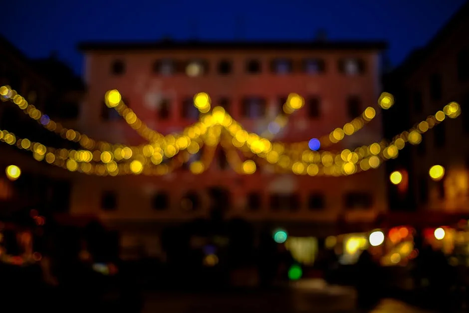 Out-of-focus warm string lights draped across a nighttime piazza in Pisa