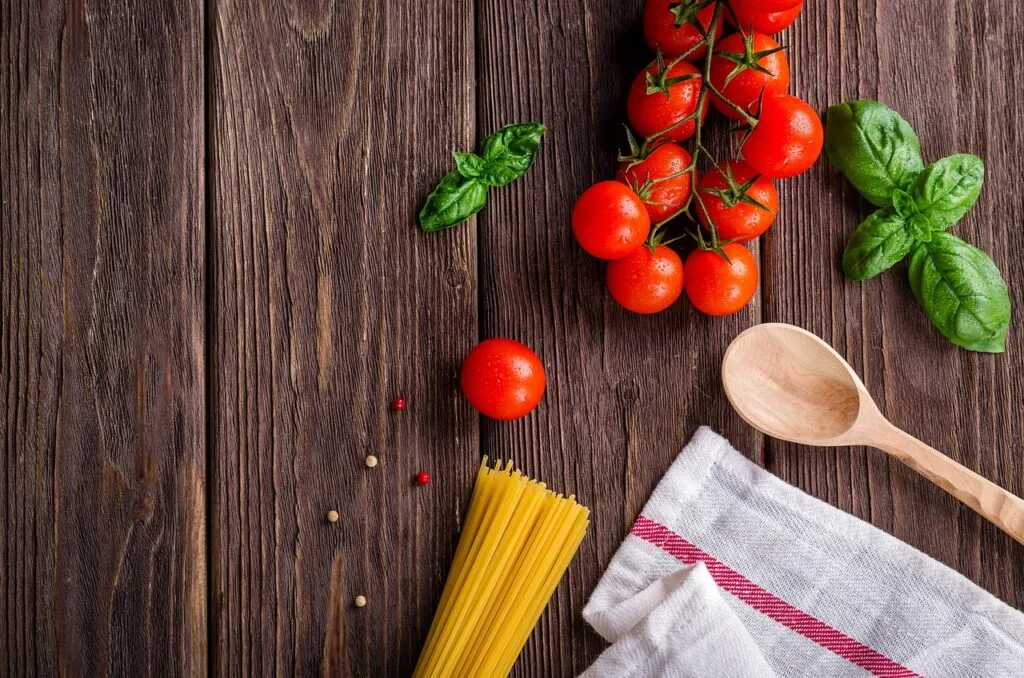 Składniki: spaghetti, pomidorki koktajlowe i świeża bazylia na stole