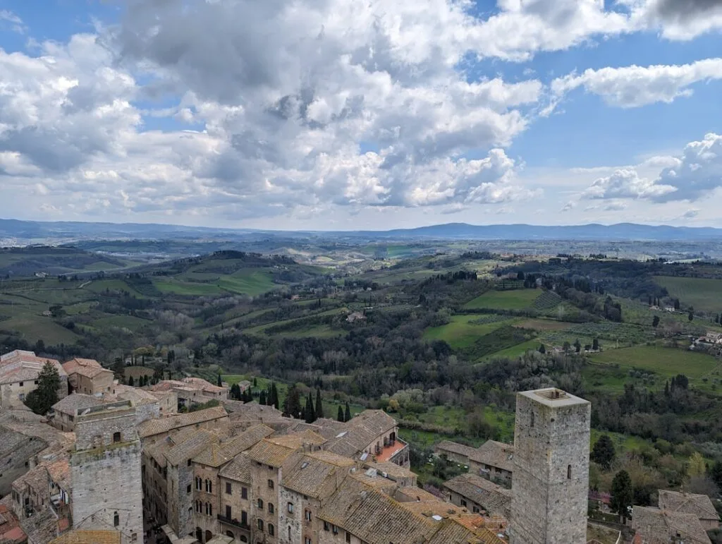 Rozległe toskańskie krajobrazy z dachami i wieżą San Gimignano