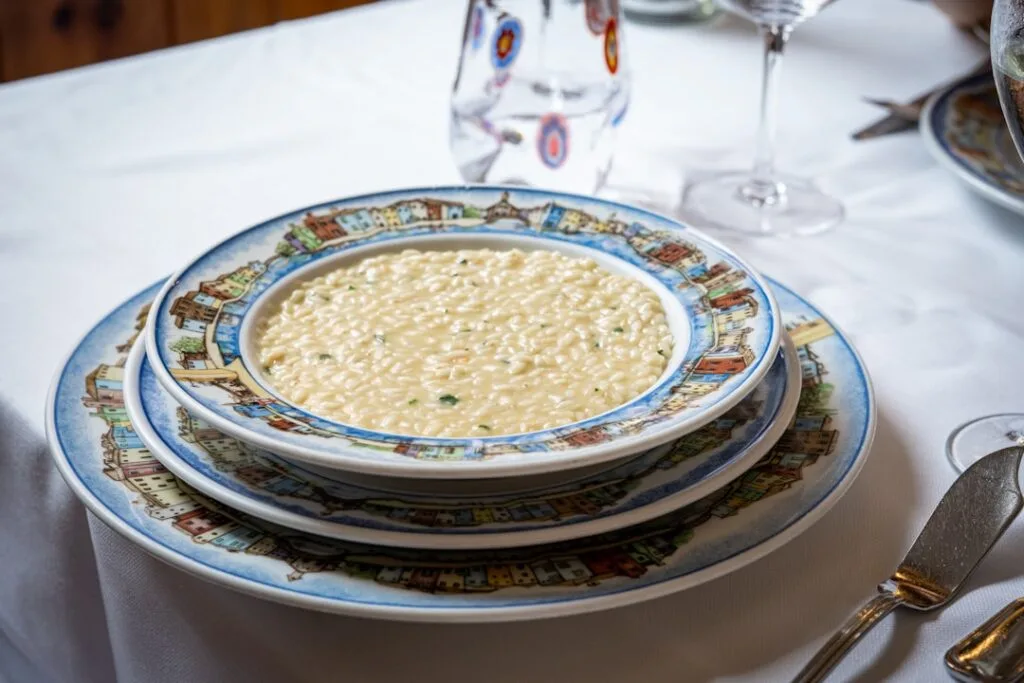 Kremowe risotto podane na ozdobnym talerzu na białym obrusie