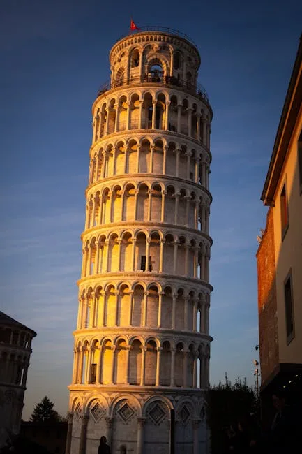 Torre di Pisa illuminata al tramonto con edifici circostanti visibili