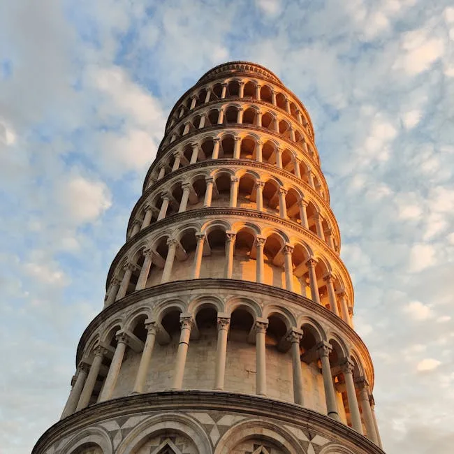 Torre di Pisa ripresa dal basso al tramonto con cielo nuvoloso
