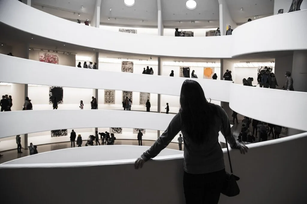 Wnętrze białej galerii z spiralnymi balkonami i zwiedzającymi